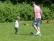 Ein Vater spielt mit seinem Sohn Fußball auf einer Wiese.